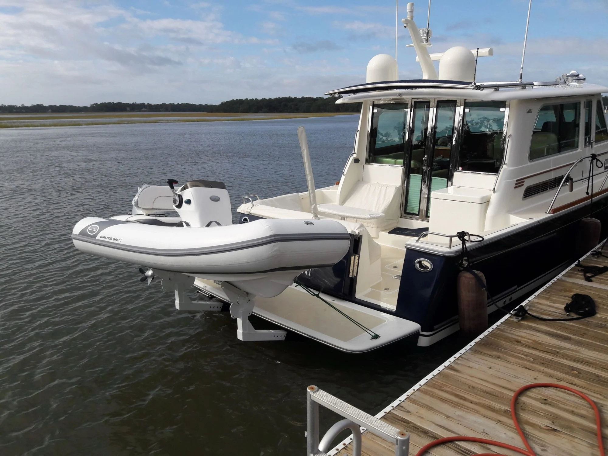 Inflatable tender on davits behind a motor yacht at the dock