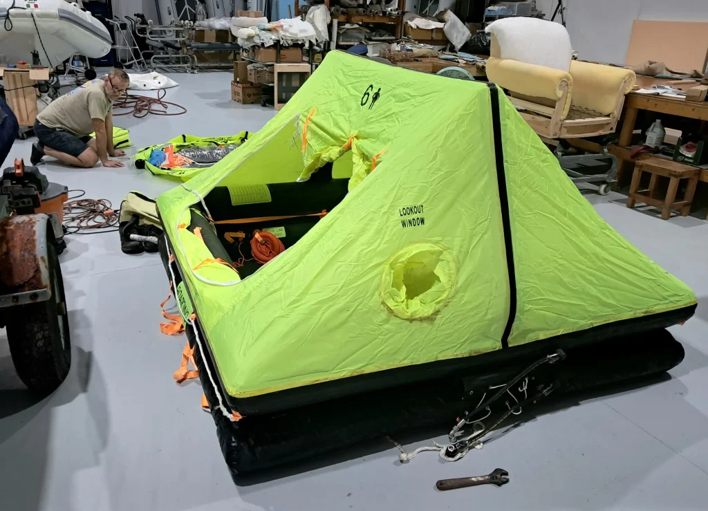 Inflated yellow-green liferaft with an open canopy in the workshop